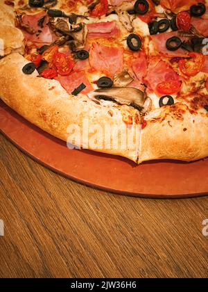 Pizza capriciosa con crosta di formaggio farcito in pizzeria, primo piano Foto Stock