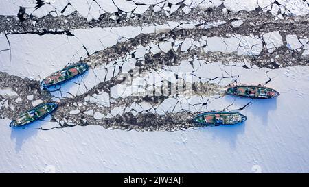 Quattro rompighiaccio che tritano ghiaccio sul fiume. Veduta aerea della natura in inverno. Veduta aerea della natura in inverno Foto Stock