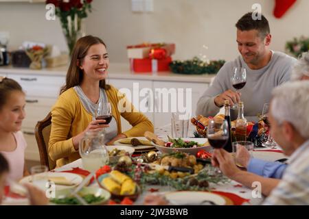 Famiglia caucasica multigenerata seduta al tavolo e sorridente Foto Stock