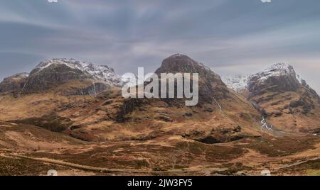 Epica immagine del paesaggio invernale della catena montuosa delle tre Sorelle innevate nelle Glencoe Scottish Highands con un cielo spettacolare Foto Stock
