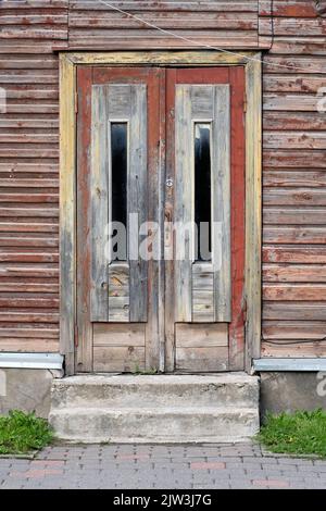 Vecchie porte di legno rosso, ingresso alla casa di legno con vernice di peeling appassita sulle pareti in a Tartu, Estonia. Foto Stock