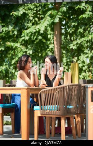 Giovani donne gioiose e graziose che si siedono in un bar all'aperto dopo lo shopping Foto Stock