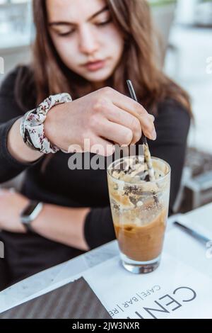 Una donna caucasica che mescola una frappa di caffè Foto Stock