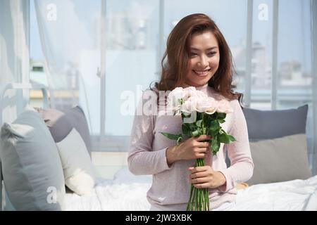 Ritratto di bella giovane vietnamita con un bouquet di rose rosa Foto Stock