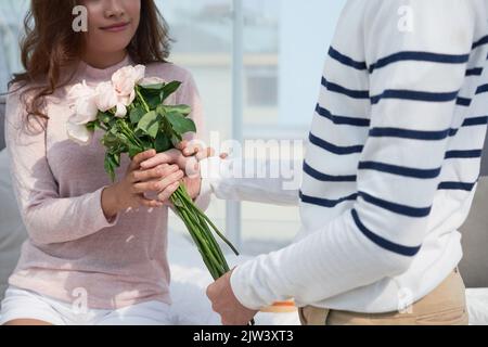 Immagine ritagliata dell'uomo che dà fiori alla sua ragazza Foto Stock