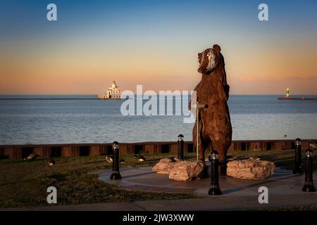 Il sole tramonta su Shipbuilder, una statua di tasso alta 12 metri, creata dallo scultore Carl Vanderheyden che si erge al porto di Manitowoc, Wisconsin. Foto Stock