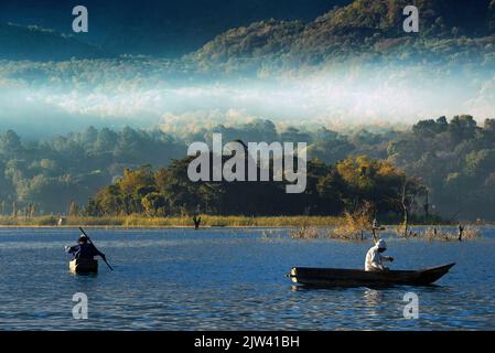 Uomini che pescano in modo tradizionale nel lago Atitlan il più grande lago del Guatemala. Laghi inquinati. Le acque del lago Atitlán diventano verdi a causa del Foto Stock