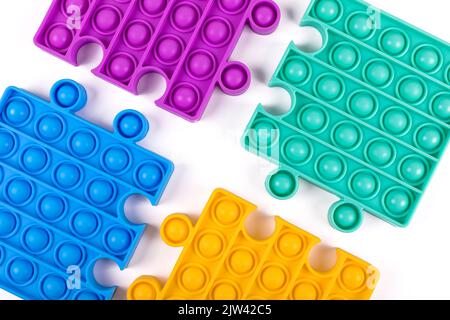 Set di famosi giocattoli colorati fidget pop su sfondo blu. Nuovi giocattoli antistress sensoriali per bambini e adulti. Giocattoli a bolle di spinta alla moda. Giacitura piatta. Foto Stock