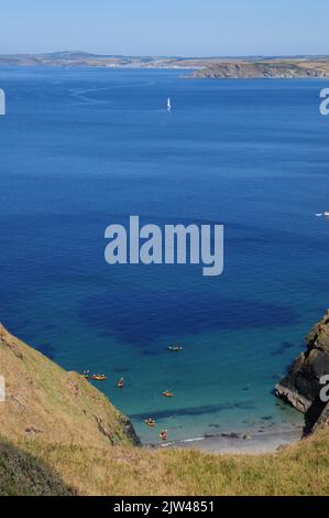 I kayakers atterrano su una spiaggia di sabbia isolata in una giornata di sole e mare calmo. Foto Stock