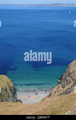 I kayakers atterrano su una spiaggia di sabbia isolata in una giornata di sole e mare calmo. Foto Stock