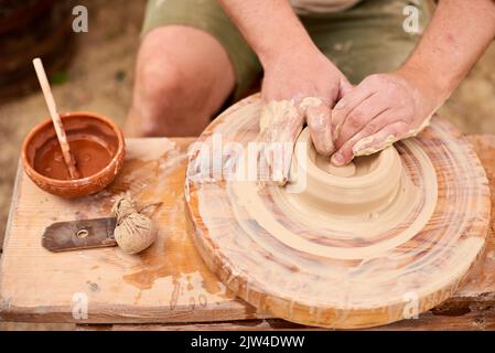 primo piano mani maschili in lavoro con argilla bianca. master in camicia di lino chiaro fare ciotola Foto Stock