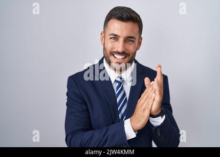 Bell'uomo ispanico che indossa abiti e cravatta che applaude mani felici e gioiose sorridendo fieri insieme Foto Stock