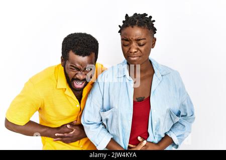 Giovane coppia afroamericana che indossa abiti casual con mano sullo stomaco perché indigestione, dolorosa sensazione di malessere. Concetto di dolore. Foto Stock