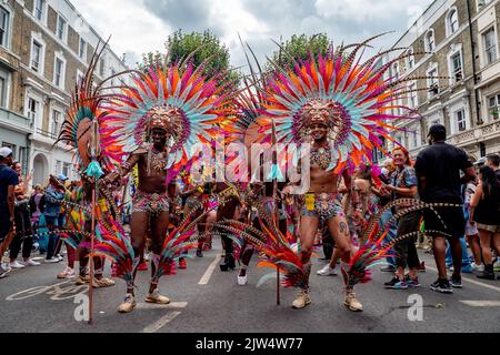 Londra, Inghilterra, Regno Unito - 29 agosto 2022: Giovane gruppo di africani vestiti per il carnevale con piume in diversi colori sulle strade, a Notting Hill Foto Stock