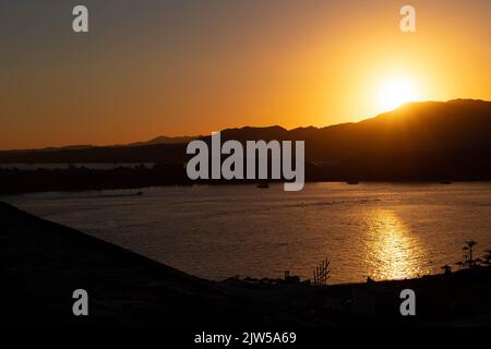 Vista aerea sul mare calmo e sulle montagne al tramonto. Spiaggia di sabbia con costa rocciosa e palme. Bellissimo paesaggio con orizzonti in estate sera raggi, Sharm El Sheikh, Egitto, banner. Foto Stock