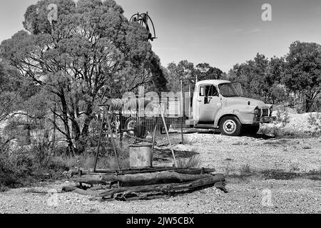 Bianco-nero a contrasto con il pozzo aperto della miniera e il camion della ruggine in Lightning Ridge, città mineraria opale di NSW Outback, Australia. Foto Stock