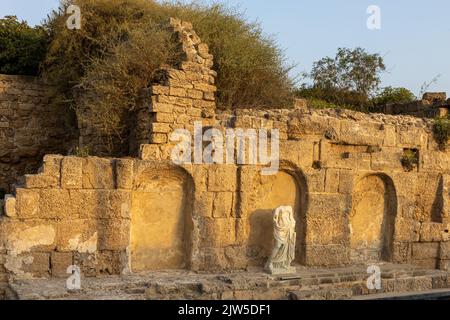 CESAREA, Israele - 2022 agosto, statua dell'imperatore romano che riflette in una piscina, numerosi turisti visitare rovine fortezza costruita da Erode il Grande vicino a Cesare Foto Stock