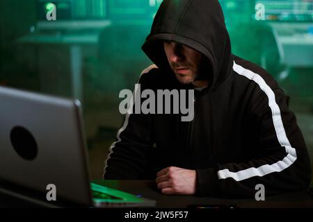 Pirata informatico che digita il codice sulla tastiera in tarda serata lavorando e bypassando la sicurezza informatica. Foto Stock