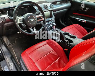 Kiel, Germania, 03. Settembre 2022: Vista laterale del volante della Ford Mustang 2018 modello vettura sportiva con sedili in pelle rossa Foto Stock