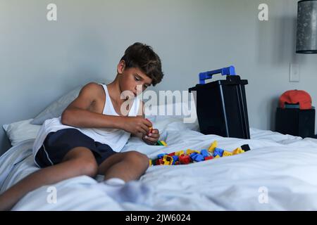 I bambini imparano così tanto con il gioco. Un ragazzo che gioca con i giocattoli sul suo letto a casa. Foto Stock