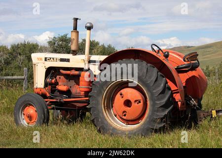 Vecchi macchinari agricoli in un campo al Bar U Ranch National Historic Site, Alberta meridionale, Canada. Trattore Case 930 vintage Foto Stock