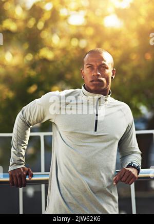 Il corpo raggiunge ciò che la mente crede. Un giovane uomo sportivo in piedi fuori. Foto Stock