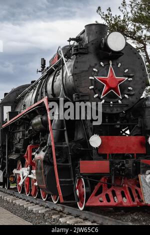 Mostra all'aperto vintage o museo, locomotiva nera con ruote rosse stella rossa. Locomotiva retrò, locomotiva a vapore sovietica su rotaie. Focalizzazione selettiva. Foto Stock