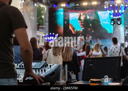 DJ mixing, computer portatile all'aperto durante il festival con una folla di persone in background. Concetto di divertimento, estate, gioventù, vita notturna, musica e intrattenimento. Basso l Foto Stock