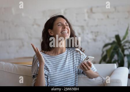 Donna overjoyed tiene smartphone delizia momento di vittoria della lotteria Foto Stock