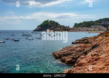 Baia della Costa Brava con piccole barche e persone che si godono sulla spiaggia, Tossa de Mar, Girona. Foto Stock