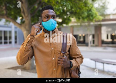 Uomo afroamericano a piedi che parla su uno smartphone Foto Stock