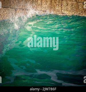 Belle onde che si lavano nel molo e porto di Porthleven. Acqua acquatica brillante. Foto Stock