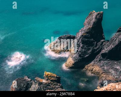 Rallentamento del tempo di scatto per una velocità dell'otturatore prolungata nella baia di Kynance. Mare estivo tropicale con morbide onde nebbie. Paradiso. Foto Stock