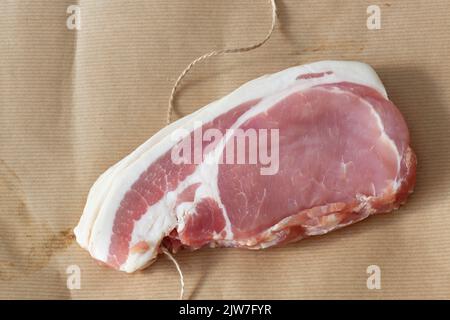 Fettine di pancetta cruda affumicata e tagliata, avvolte in carta marrone con filo, imballo ecologico Foto Stock
