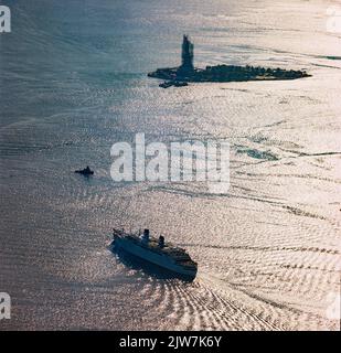 New York, 1980s, nave Britanis liner, Liberty Island in The Distance, Statua della libertà con ponteggi ristrutturati, riflessi di luce sull'acqua, Upper New York Bay, aereo, New York City, NYC, NY, STATI UNITI, Foto Stock