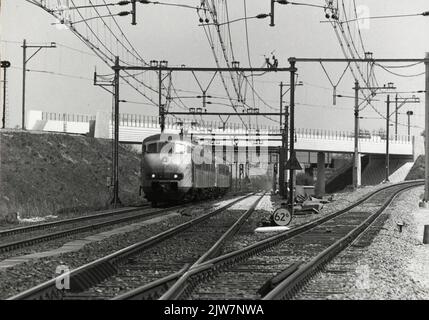 Vista del nuovo volo per la linea ferroviaria verso Rhenen sulla linea Utrecht-Arnhem al collegamento dei capelli, con due treni elettrici collegati Matt. 1964 (piano V) sulla strada per Utrecht. A sinistra in primo piano la pista in salita verso Rhenen e sullo sfondo, dietro il nuovo viadotto, il viadotto della linea ferroviaria Amersfoort-Kesteren. Foto Stock