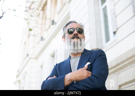 uomo anziano che indossa un vestito e occhiali da sole visti dal basso in un luogo all'aperto Foto Stock