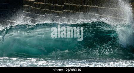 Belle onde che si lavano nel molo e porto di Porthleven. Acqua acquatica brillante. Foto Stock