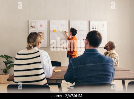 Manager che presenta il suo team durante una riunione. Il team leader maturo presenta la sua idea ai suoi colleghi. Gruppo di diverse imprese Foto Stock