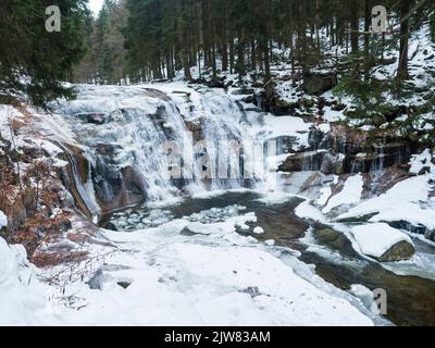 Mumlavsky vodopad, cascata sul torrente Mumlava nel Parco Nazionale di Krkonose, Repubblica Ceca in inverno foresta coperta di neve Foto Stock