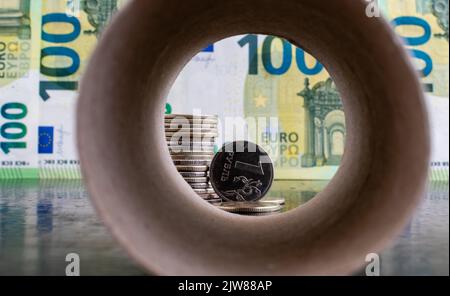 1 primo piano della moneta rublo russa sullo sfondo delle banconote in euro all'interno di un fondo di tubo di carta sfocato Foto Stock