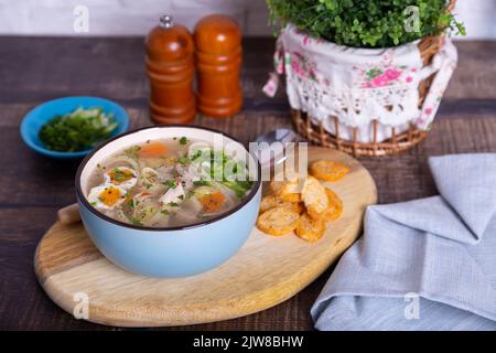 Zuppa con pollo, tagliatelle, patate, uova di quaglia e carote. Condito con cipolle e prezzemolo. Primo piano. Foto Stock