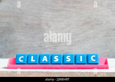 Piastrella lettera alfabetica con parola classica in rack di colore rosso su sfondo di legno Foto Stock