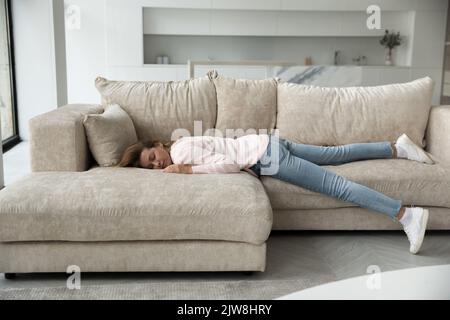 Giovane donna addormentata che riposa sul divano di casa ripresa a tutta lunghezza Foto Stock