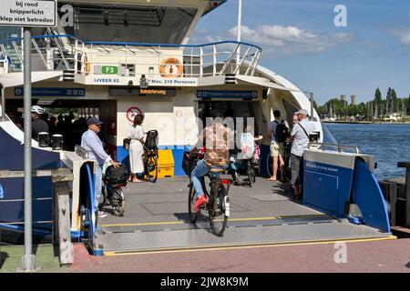 Amsterdam, Paesi Bassi - 2022 agosto: Giro del ciclista su un traghetto fluviale sul lungomare del centro città Foto Stock