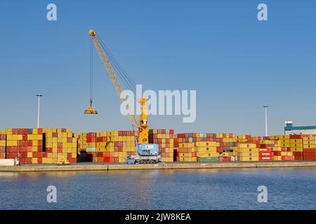 Anversa, Belgio - Agosto 2022: Gru e contenitori di spedizione immagazzinati sul lato del porto commerciale della città Foto Stock