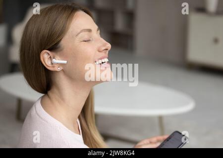 Felice donna millenaria entusiasta che ascolta la musica che ispira Foto Stock