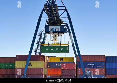 Rotterdam, Paesi Bassi - Agosto 2022: Grande gru mobile che solleva un container di spedizione sul molo sul fiume vicino Rotterdam Foto Stock