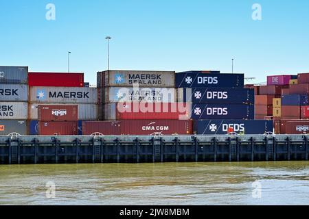 Rotterdam, Paesi Bassi - Agosto 2022: Container per la navigazione industriale impilati sul molo del fiume vicino Rotterdam Foto Stock