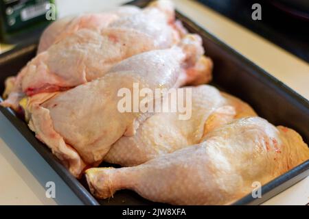 Vista ad angolo alto delle cosce di pollo crude nella teglia da forno sopra il tavolo Foto Stock